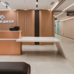 Designer administrator counters for clinics Assembly of the central radiused reception counter with decorative copper-toned metal panels and veneer elements. Premium furniture for entrance groups.