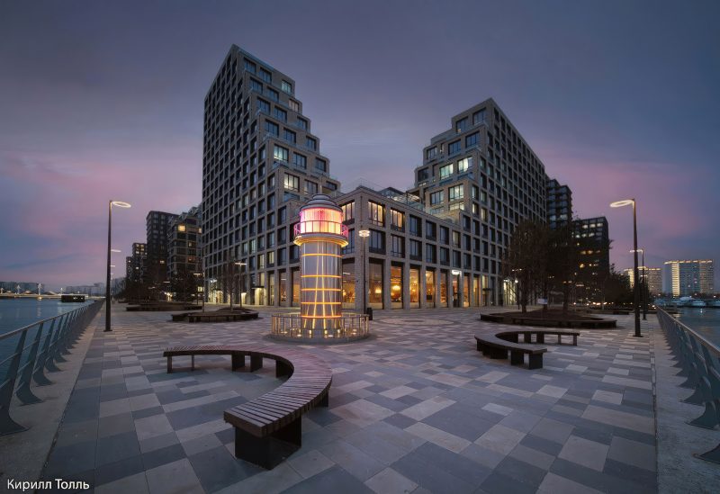 Вечерний маяк в Ривер Парке, белая башня с подсветкой на фоне темнеющего неба и ЖК, Нагатинский затон, Москва