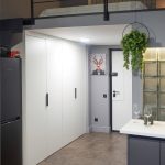 Двухуровневый лофт в ЖК Loftec: прихожая со встроенным белым шкафом, чёрный холодильник, кухня со стеклоблоками и спальня на втором ярусе — фото Кирилла Толль