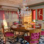 Парадная столовая в ЖК Новопесковский (Арбат): круглый антикварный стол, стулья с малиновой обивкой, муранская люстра и стены с помпейской росписью в лучах солнца — фото Кирилла Толль