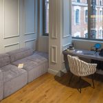 Зона отдыха с низким серым диваном и встроенный рабочий стол у окна в апартаментах ЖК Loftec — съёмка Кирилла Толль