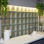 Кухонная зона в ЖК Loftec со светящимся фартуком из матовых стеклоблоков, белой столешницей и симметричными подвесными растениями — фото Кирилла Толль