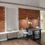 Широкий план обеденной зоны и кирпичной стены с видом на кухню в квартире у метро Трубная — фото Кирилла Толль