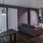 Вид на обеденную группу и диванную зону в квартире у метро Трубная — тёмный стол, сиреневая стена и встроенный стеллаж. Съёмка: Кирилл Толль