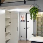 Прихожая в ЖК Loftec с открытым белым шкафом, видом на антресоль со спальней и кухню со стеклоблоками — съёмка Кирилла Толль