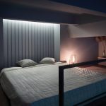 Интерьер спальни на антресоли в ЖК Loftec с кроватью, стеной из реек с подсветкой и круглым зеркалом — съёмка Кирилла Толль