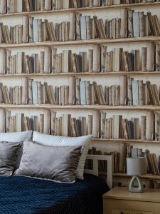 Акцентные обои под книги в изголовье кровати и синее покрывало в спальне у Патриарших прудов
