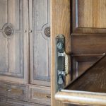 Деталь антикварного шкафа на Большой Полянке: латунная дверная ручка с патиной, декоративная резьба по дубу.