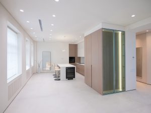 Современная кухня с белым островом, винным шкафом и встроенной техникой