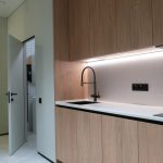 Интерьер малогабаритной кухни из шпона дерева с черным смесителем и подсветкой фартука фотограф Кирилл Толль