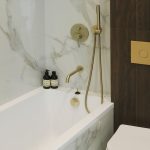 Детальный вид сантехники в ЖК Level Причальный: встроенный золотой смеситель, душевая лейка, кнопка инсталляции.