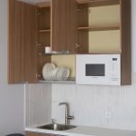 Верхние шкафы кухни: открытая сушилка с посудой и встроенная микроволновая печь. ЖК Матвеевский парк.