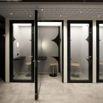 Номерованные телефонные будки VK Phone Booths (кабины 1 и 2) с открытыми стеклянными дверями, внутренними барными стульями и звукопоглощающим навесом.