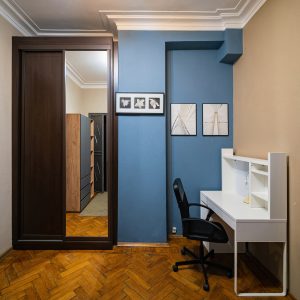 Рабочая зона с белым столом, шкафом-купе и синей акцентной стеной в квартире между Маяковской и Пушкинской