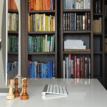 Современный домашний офис: белый стол с iMac, шахматы и встроенный книжный шкаф. Фотограф Кирилл Толль.