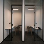Персональные офисные боксы для уединённой работы с подвесными линейными светильниками и лаконичными столами и креслами.