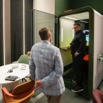 Диагональная композиция среднего плана. Рустем Мамин стоит спиной к камере, координируя внимание зрителя на Денисе Медведеве, который находится внутри открытой акустической кабины SPACELINE. Наглядно продемонстрирована вместительность капсулы тишины относительно роста взрослого человека.