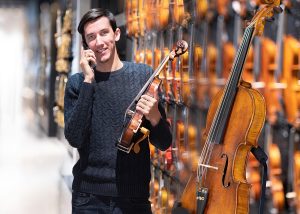 портрет мужчины, консультирующего покупателя по телефону. Самый старший продавец роялей и клавишь