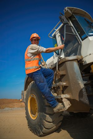 Парень забирается на трактор, портрет на фоне вечернего неба