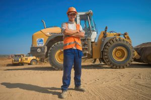 Крутой студент-строитель в каске и оранжевой жилетке, уверенный взгляд