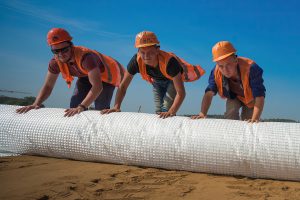 Трое рабочих улыбаются, работая вместе, командный дух стройки