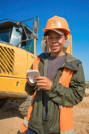 Студент с прибором контролирует въезд техники, ответственный взгляд