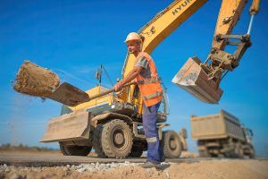 Рабочий с лопатой, портрет на фоне строительного вагончика