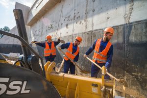 Парень отдыхает на фоне работающих товарищей, контраст отдыха и труда