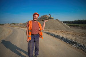 Двое студентов позируют, обнявшись на фоне трактора