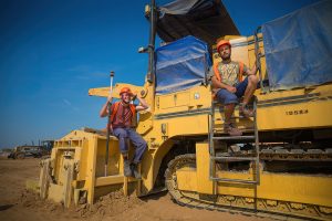 Двое парней на асфальтоукладчике, дружеский портрет на стройке