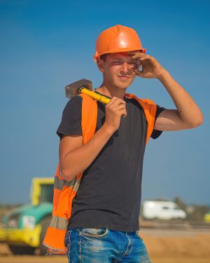 Строитель в каске с отбойным молотком, динамичный портрет на стройплощадке