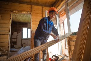 Двое рабочих в касках проверяют уровень асфальта, командный портрет на стройке